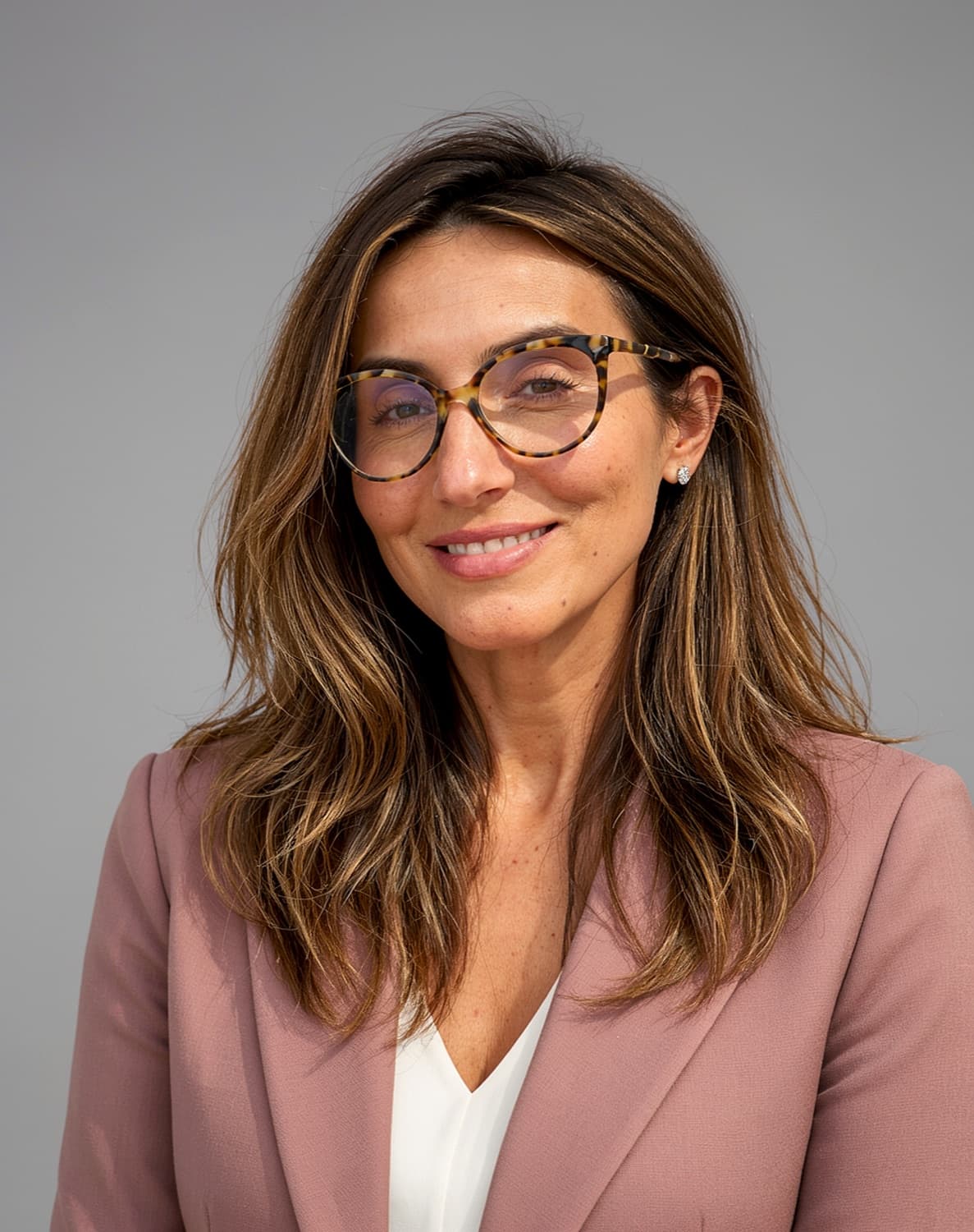 Dr. Venera Bekteshi in a rose blazer and tortoiseshell glasses, smiling